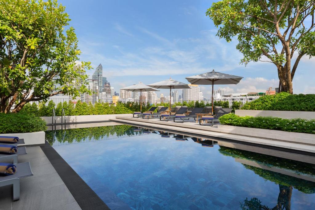 a swimming pool with chairs and umbrellas on a building at Madi Paidi Bangkok, Autograph Collection in Bangkok