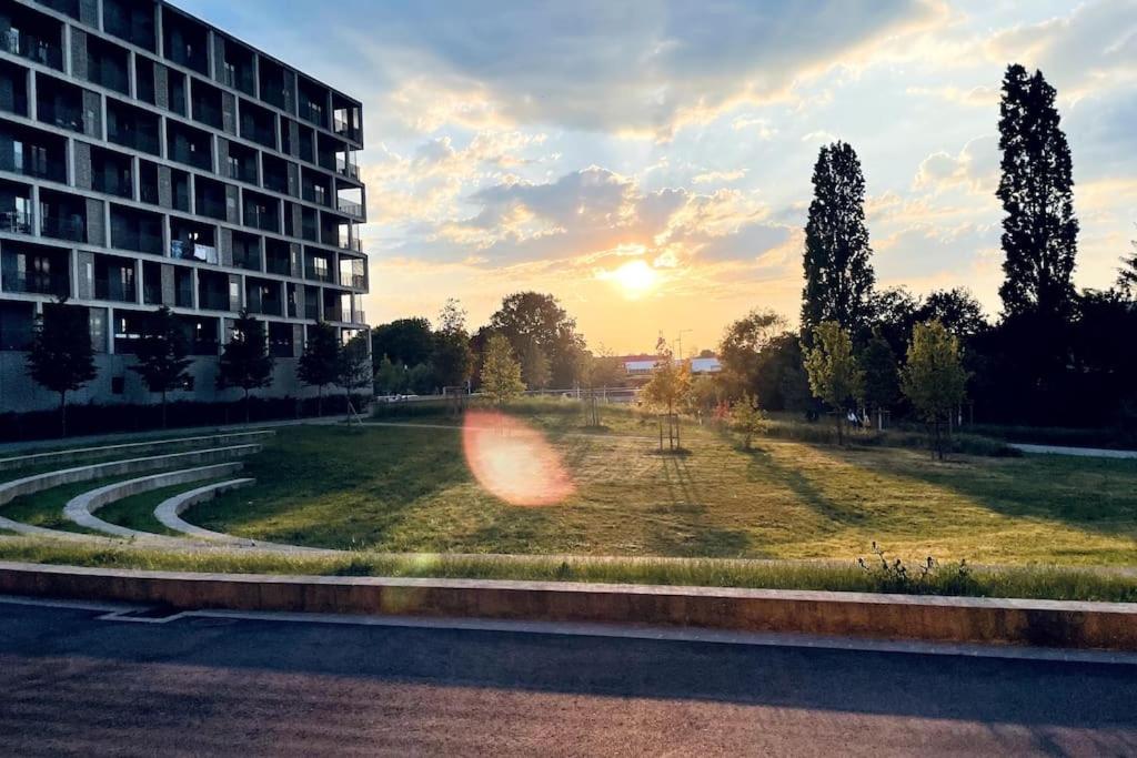 a sunset in a park with a building and trees at Beautiful High Standard Apartment in Luxembourg