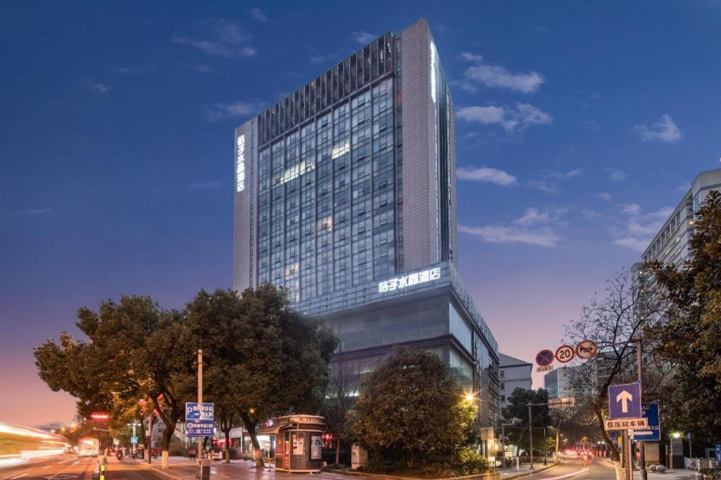 a tall building on a city street at night at Crystal Orange Hotel Wuxi Nanchang Street in Wuxi