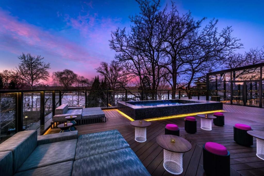 a rooftop patio with a pool and tables and benches at Blossom House Beijing Houhai in Beijing
