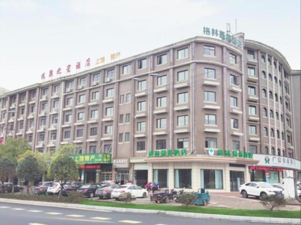 un gran edificio con coches estacionados en un estacionamiento en GreenTree Inn Shangrao Wuyishan Avenue Meide Yinxiang, en Shangrao