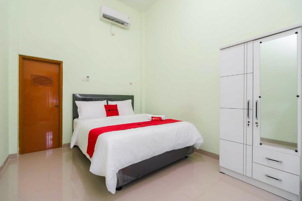 a white bedroom with a bed and a dresser at RedDoorz Syariah Near RSUD Dr HM Rabain in Muaraenim