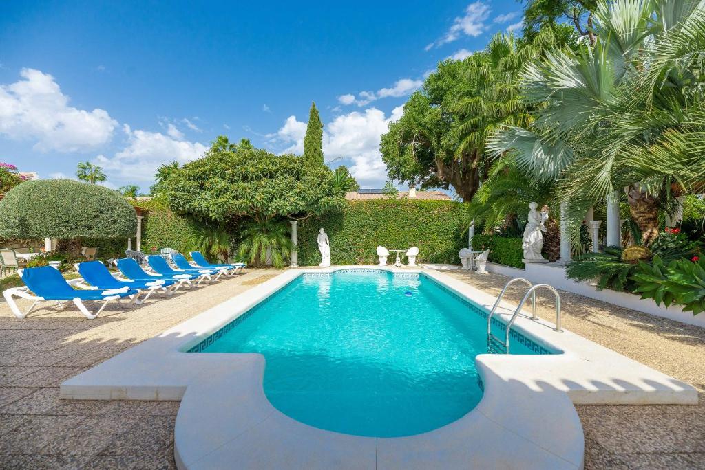 una piscina con sillas azules en un patio en Lovely Villa Las Palmeras, en Marbella