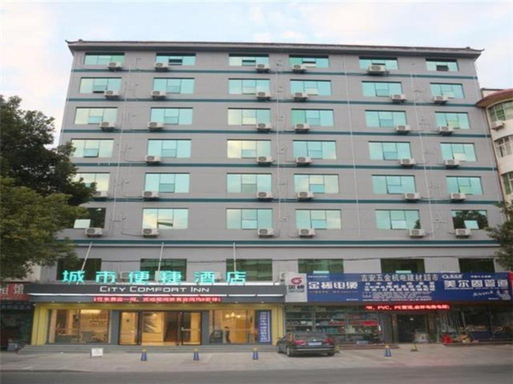 duży szary budynek z samochodem zaparkowanym przed nim w obiekcie City Comfort Inn Ji'an County Junshan Avenue w Ji'an