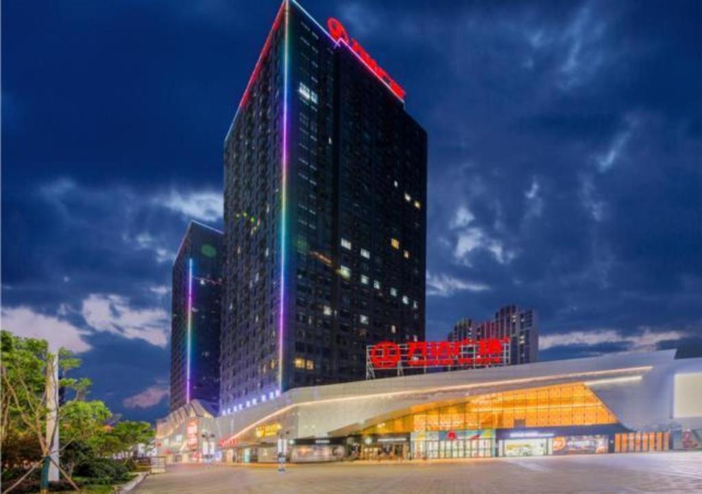 a tall building with colored lights on it at City Comfort Inn Shiyan High-speed Railway Wanda Plaza in Shiyan