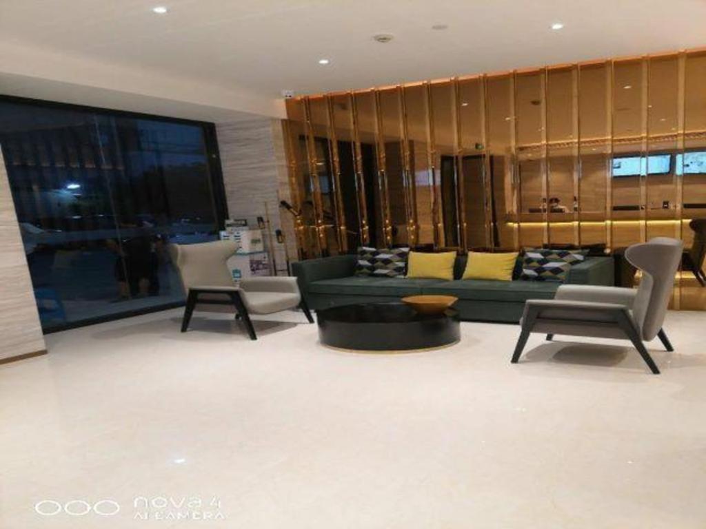 a living room with a green couch and chairs at City Comfort Inn Kunshan High-speed Railway Station Renmin Road in Kunshan