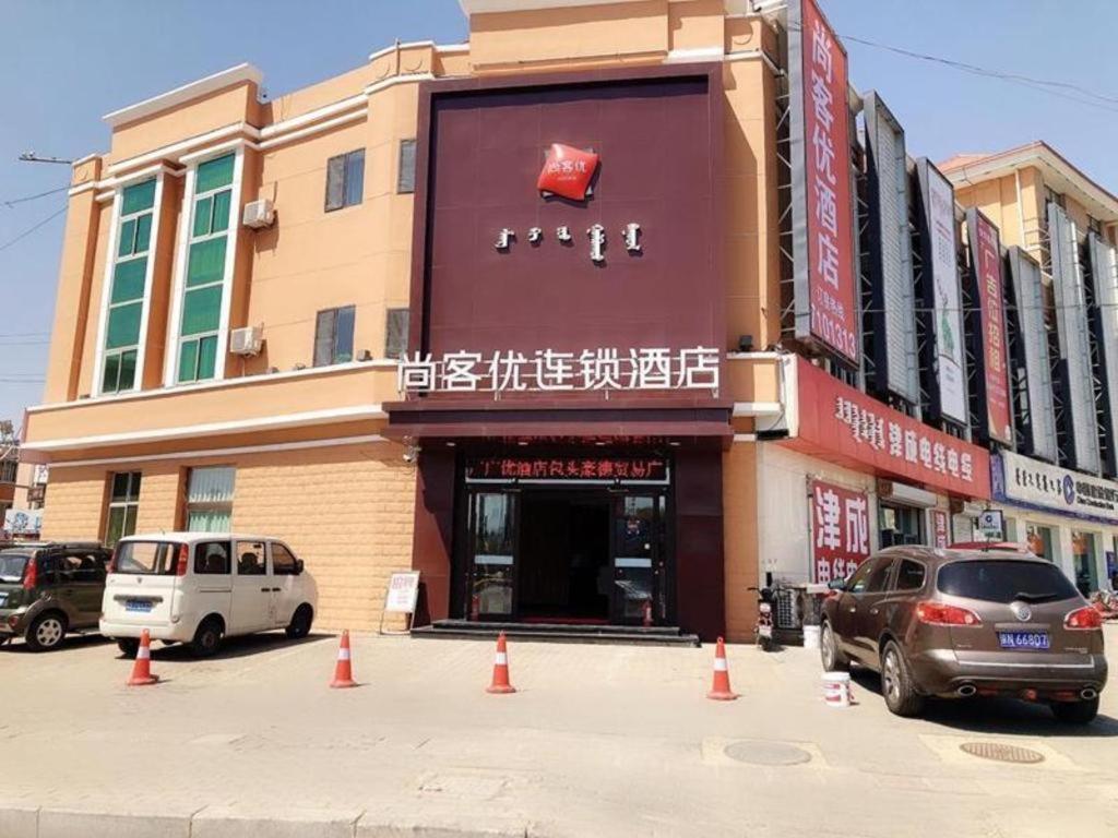 um edifício com carros estacionados em frente em Thank Inn Hotel Inner Mongolia Baotou Donghe Haode Trade Plaza em Baotou