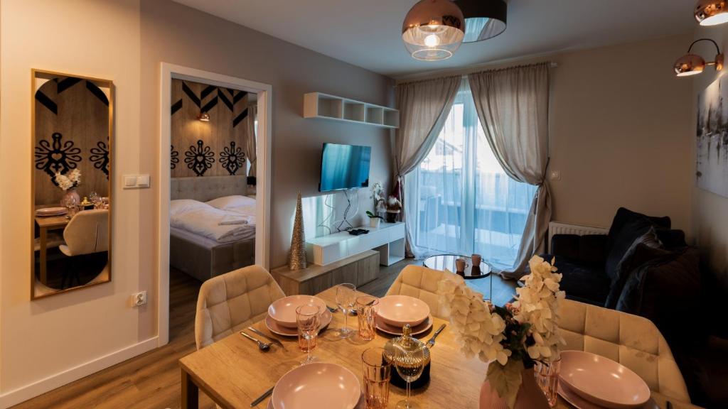a dining room with a table and a bedroom at VacationClub - Apartamenty Zakopiańskie Apartament 44 in Zakopane