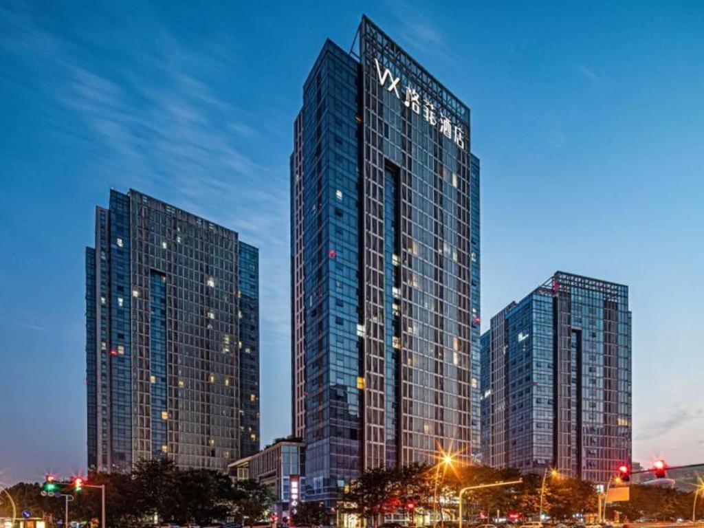 twee hoge wolkenkrabbers in een stad 's nachts bij VX Hotel Wuxi Xinwu District Executive Center Wanda Plaza in Xin'an