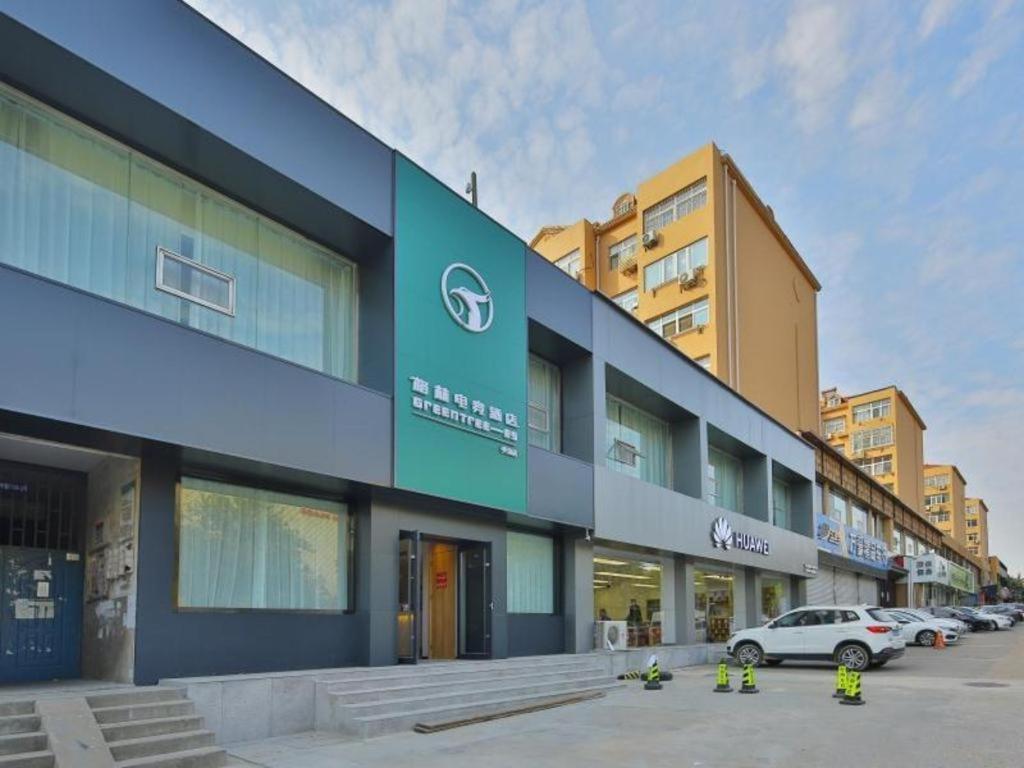 a building with cars parked in a parking lot at GreenTree Esports Hotel Qingdao Licang District Wanda in Laoshan