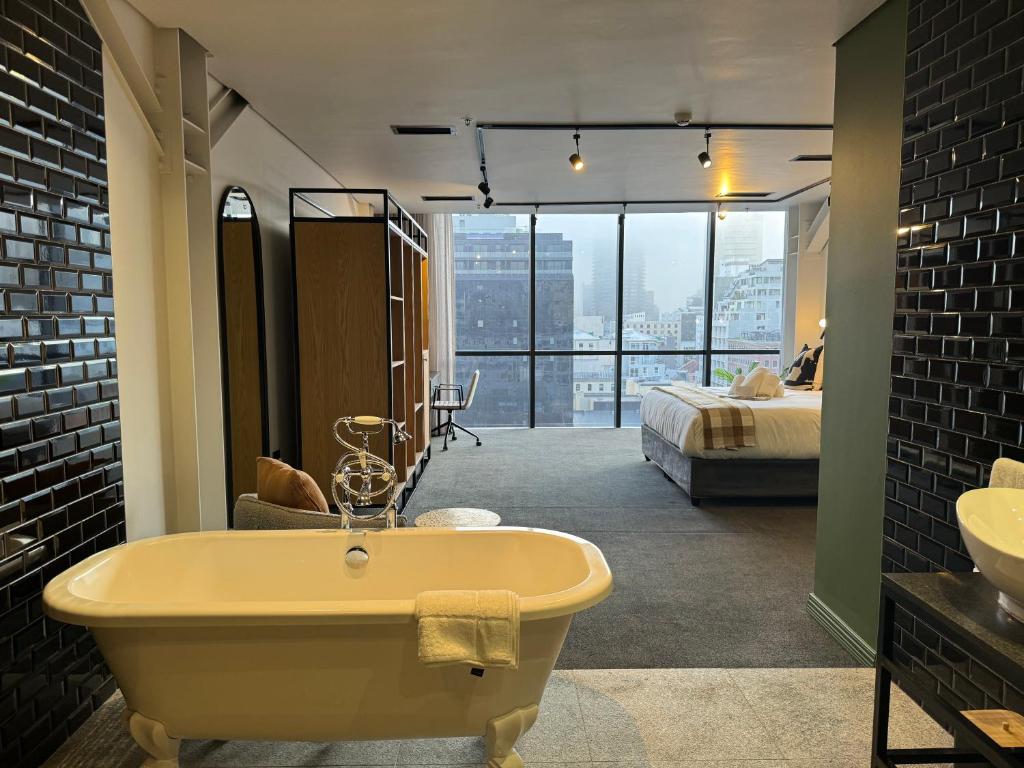 a bathroom with a bath tub and a bedroom at Neighbourgood Loop Street in Cape Town