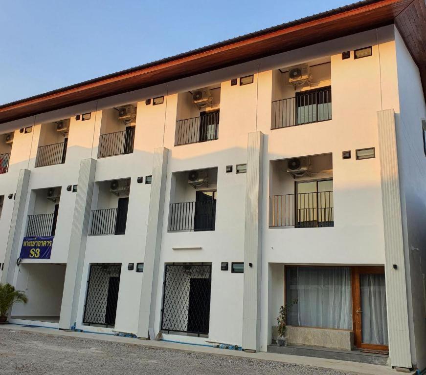un gran edificio blanco con ventanas con barrotes en S Residence (S HOTEL) en Ban Nong Pla Kho