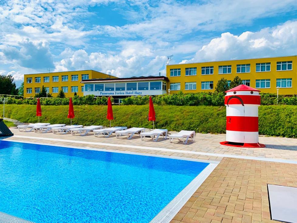 a pool with a red and white lighthouse next to a building at Panorama Ferien Hotel Harz in Güntersberge