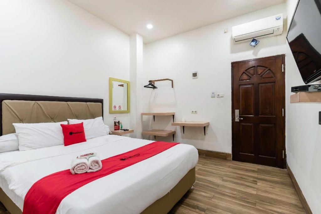 - une chambre avec un grand lit et une couverture rouge dans l'établissement RedDoorz Plus @ Jalan Veteran Palembang, à Palembang