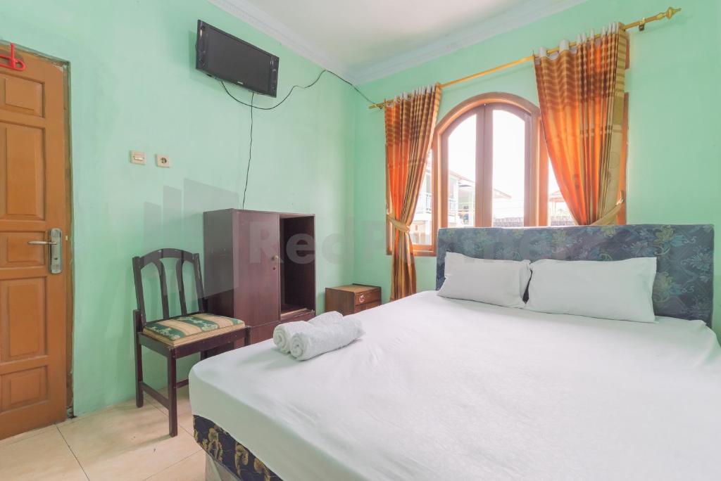 1 dormitorio con 1 cama con silla y ventana en Villa Sari Intan Ciater RedPartner en Subang