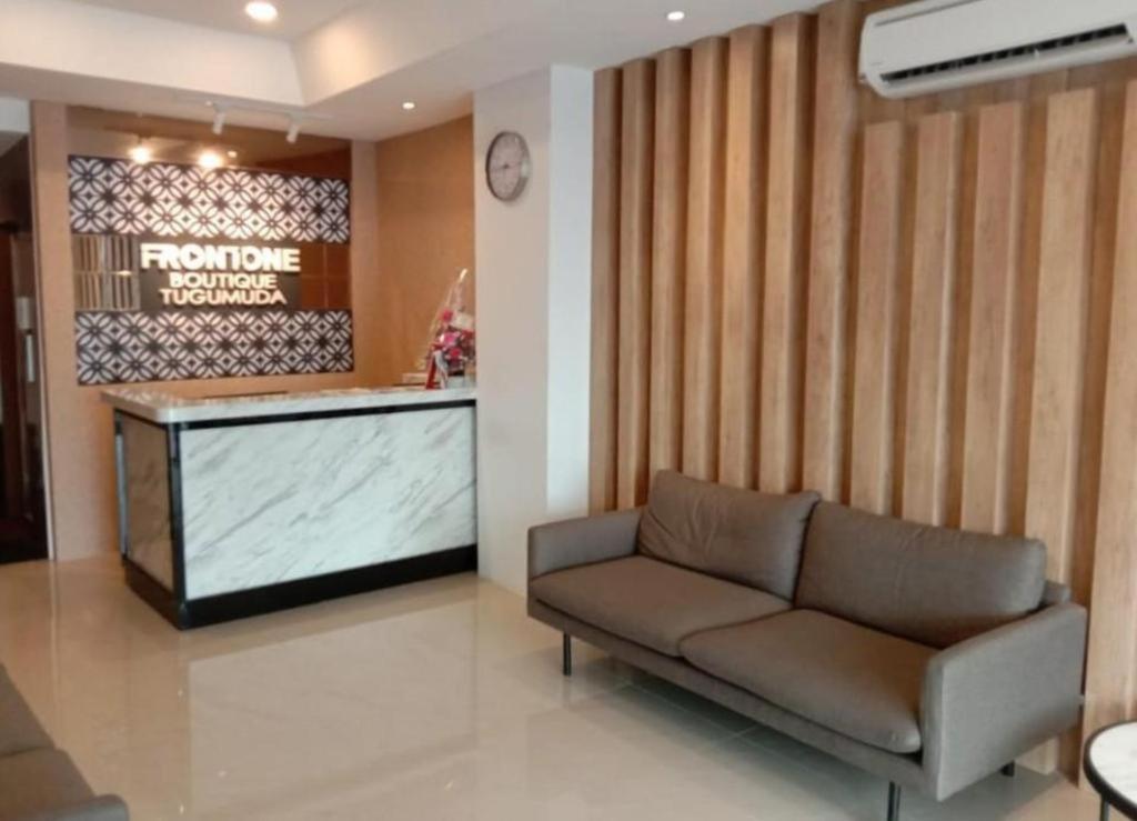 a living room with a couch and a television at Front One Boutique Tugu Muda Semarang in Semarang