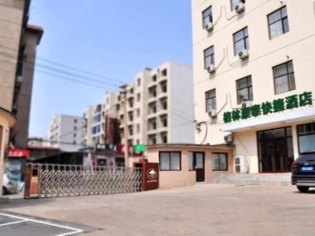 budynek na ulicy miejskiej z samochodem zaparkowanym przed budynkiem w obiekcie GreenTree Inn Dalian Jinzhou District Railway Station Ansheng Plaza w mieście Jinzhou