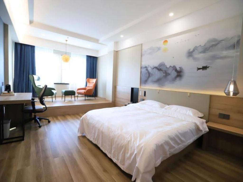a bedroom with a white bed and a desk and a desk at VX Hotel Jiangsu Taizhou Xinghua RT-Mart in Xinghua