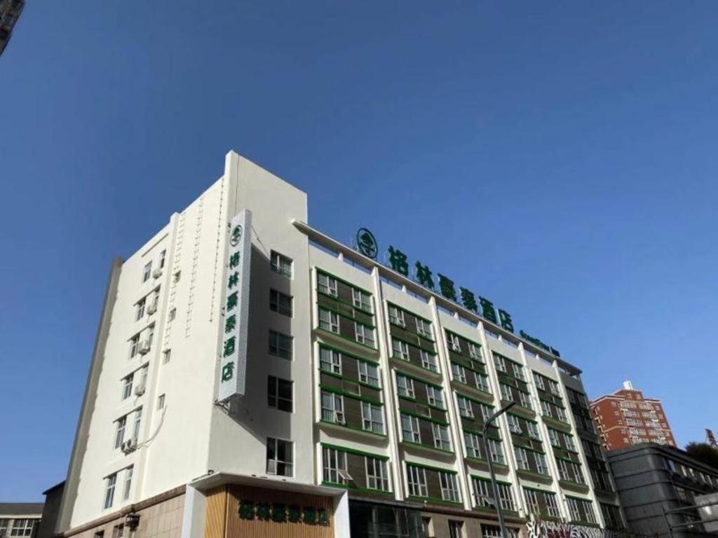 a white building with green windows on a city street at GreenTree Inn Luoyang Railway Station Wangfujing Wangcheng Park in Luoyang