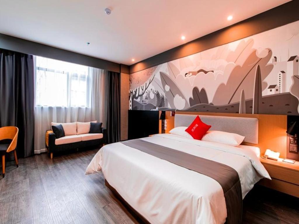 um quarto de hotel com uma cama grande e uma cadeira em Thank Inn Guizhou Bijie Qianxi County High-Speed Railway Station em Qianxi