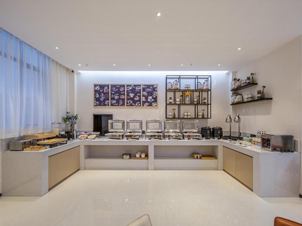 a large kitchen with a counter with stools at City Comfort Inn Wuzhou Xijiang Thrid Bridge in Cangwu