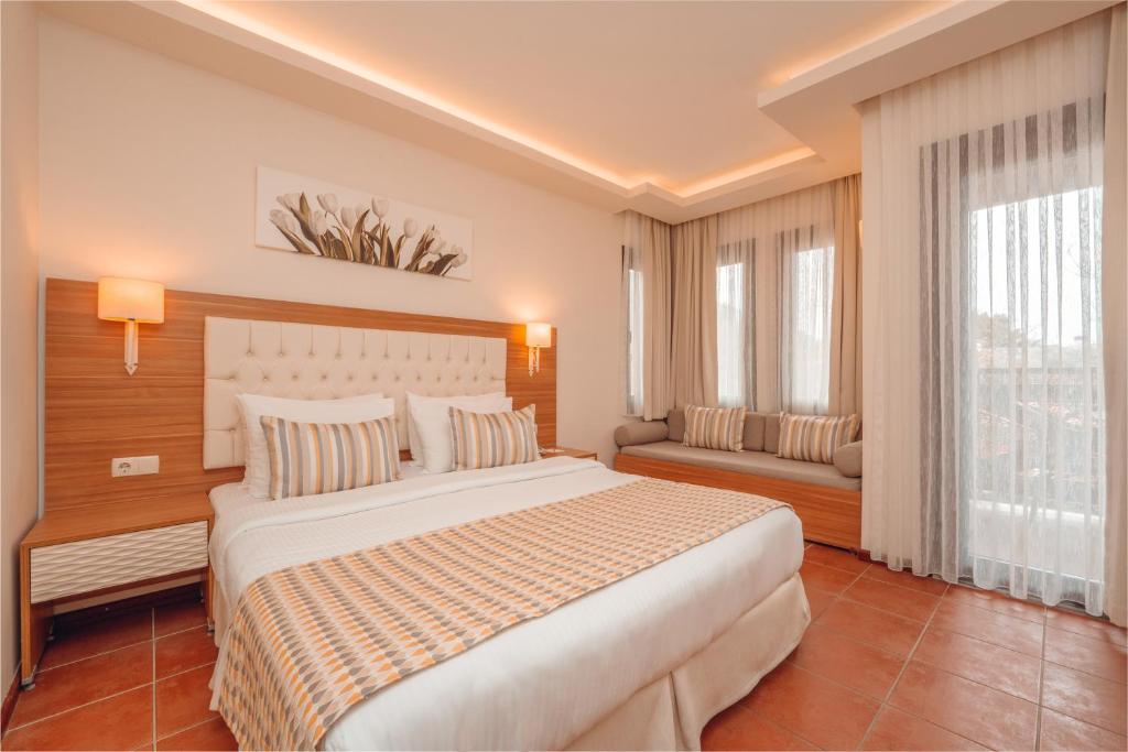 a bedroom with a large white bed and windows at Sundia By Liberty Suncity in Oludeniz