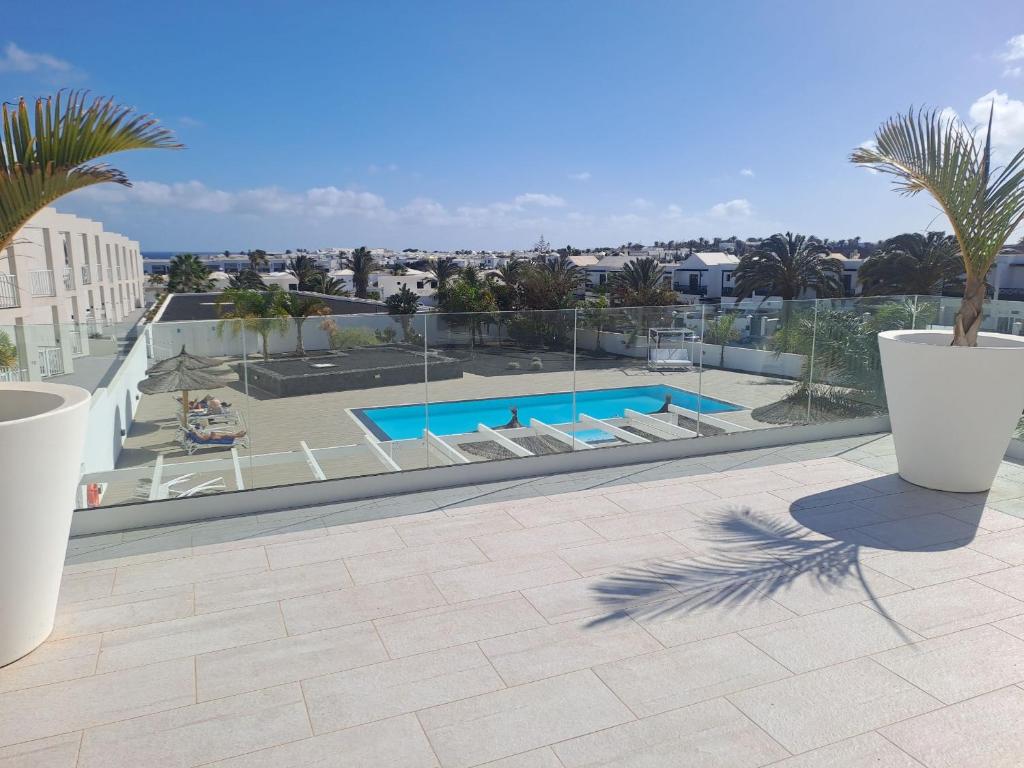 einen Balkon mit Blick auf den Pool und die Palmen in der Unterkunft Luxury Sea View Senator Lanzarote in Costa Teguise