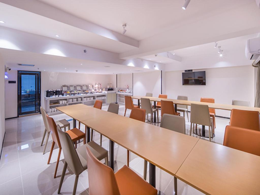 ein großes Zimmer mit Tischen und Stühlen sowie einer Küche in der Unterkunft City Comfort Inn Wuzhou Sanqi City Rose Lake Park in Wuzhou