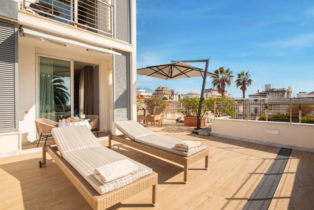 a patio with two lounge chairs and an umbrella at Hotel Excelsior in Marina di Massa