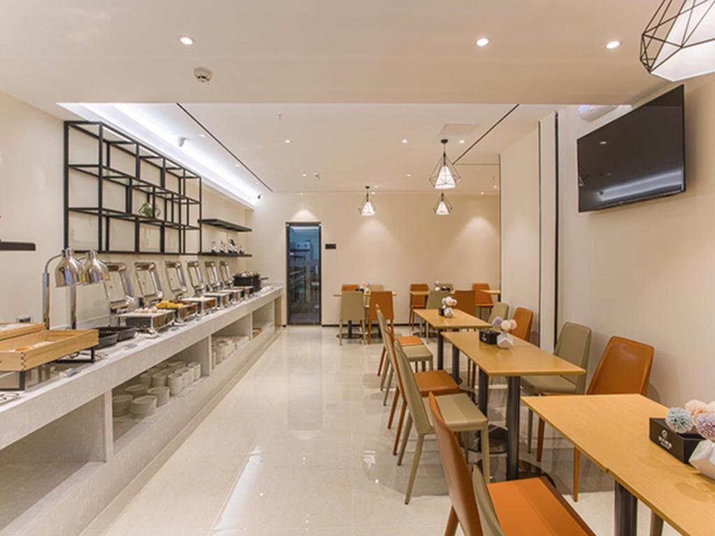 a restaurant with tables and chairs and a counter at City Comfort Inn Wuzhou Sun Plaza Wanda in Wuzhou