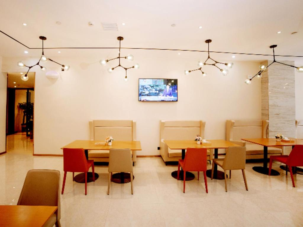 restauracja ze stołami i krzesłami oraz telewizorem na ścianie w obiekcie City Comfort Inn Ezhou Huahu Airport High-speed Railway Station w mieście Huangshi