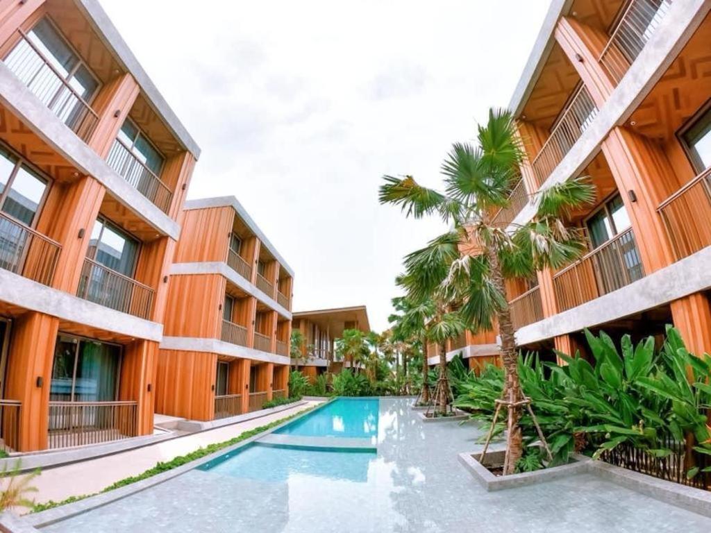 um edifício de apartamentos com piscina e palmeiras em Riverton Hotel em Samut Songkhram