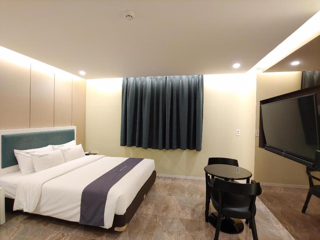 1 dormitorio con 1 cama y TV de pantalla plana en jeju illua hotel en Jeju