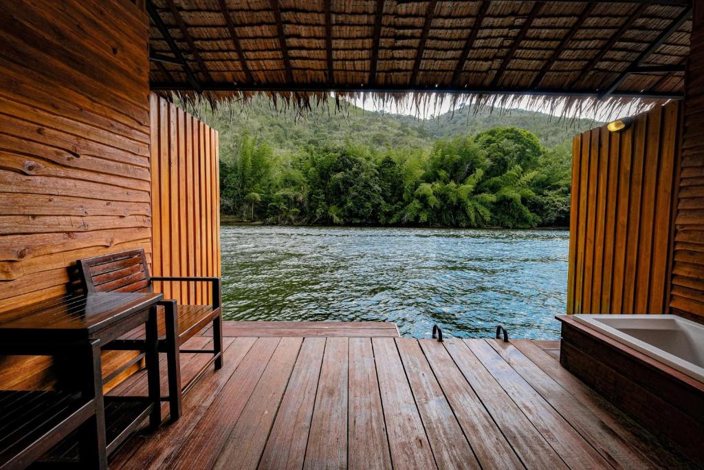 una terraza de madera con bañera y un barco en The Hub Erawan Resort en Chongsadao