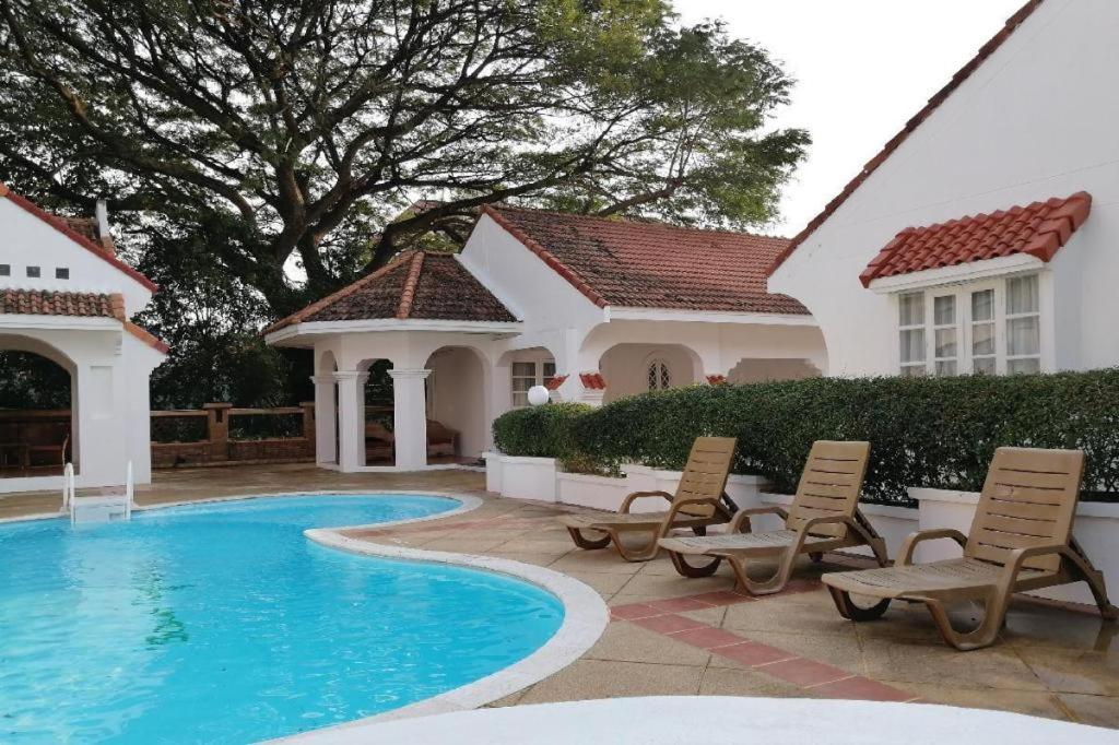 - une piscine en face d'une maison avec des chaises dans l'établissement Villa Centro Hua Hin, à Hua Hin