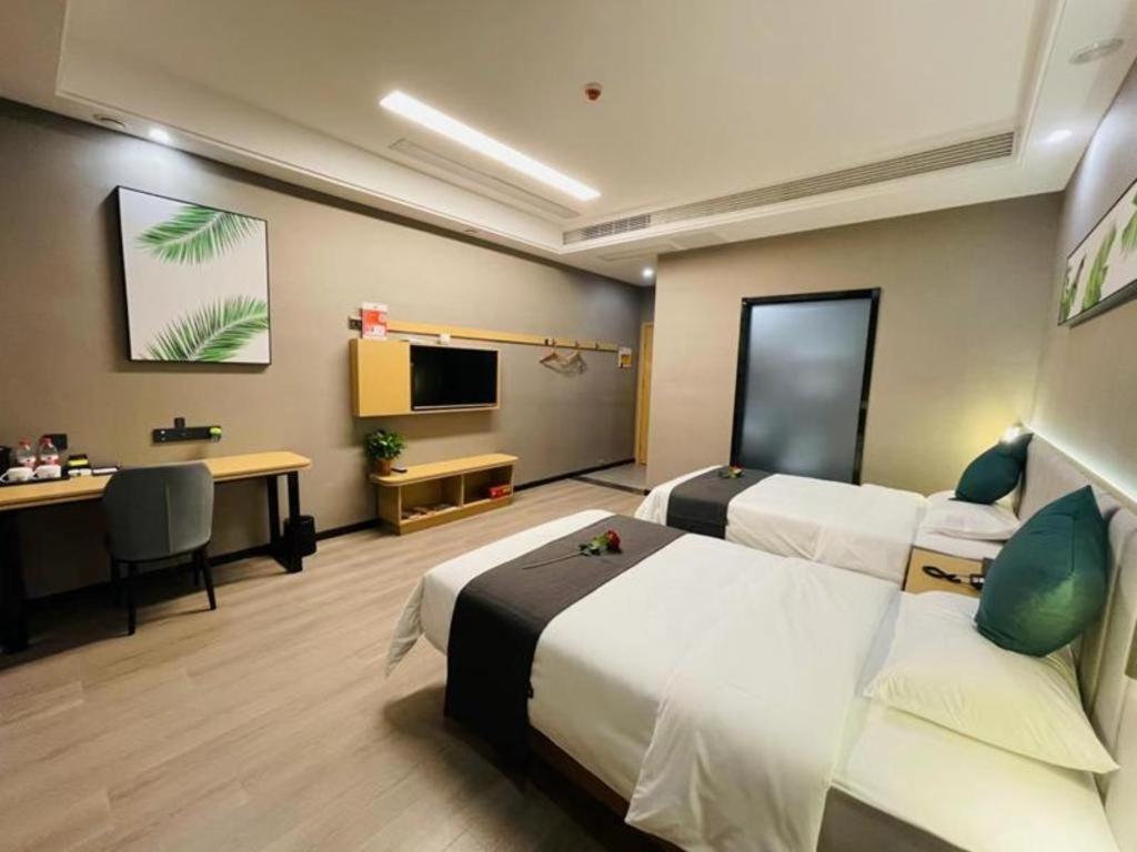 a hotel room with two beds and a desk and a television at Thank Inn Jiangsu Suqian Sucheng District Car Town in Suqian