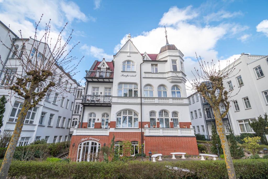 duży biały budynek z drzewami przed nim w obiekcie Hotel Imperial Rügen w mieście Binz