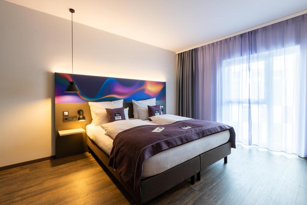 a bedroom with a large bed and a large window at the niu Wave - Apartments in Karlsruhe
