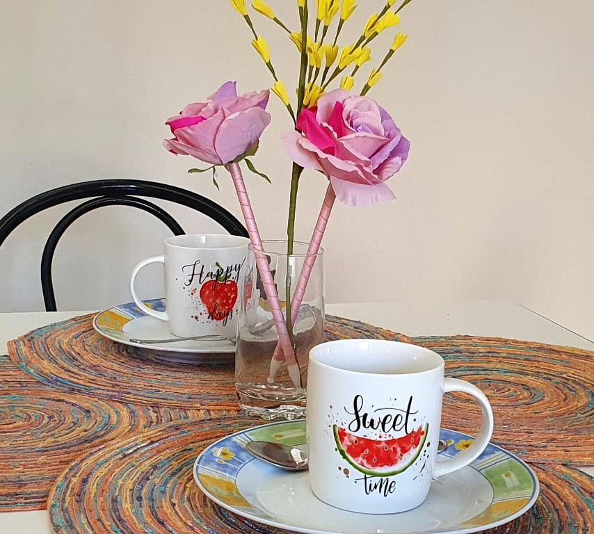 dos tazas y un jarrón con flores en una mesa en Sotto Le Stelle Home - una Baita in città, en Viterbo
