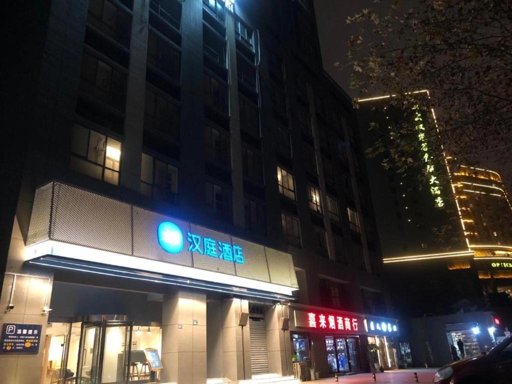 a building with a green traffic light on a street at night at Hanting Hotel Wuhan Guanggu Plaza in Liufangling