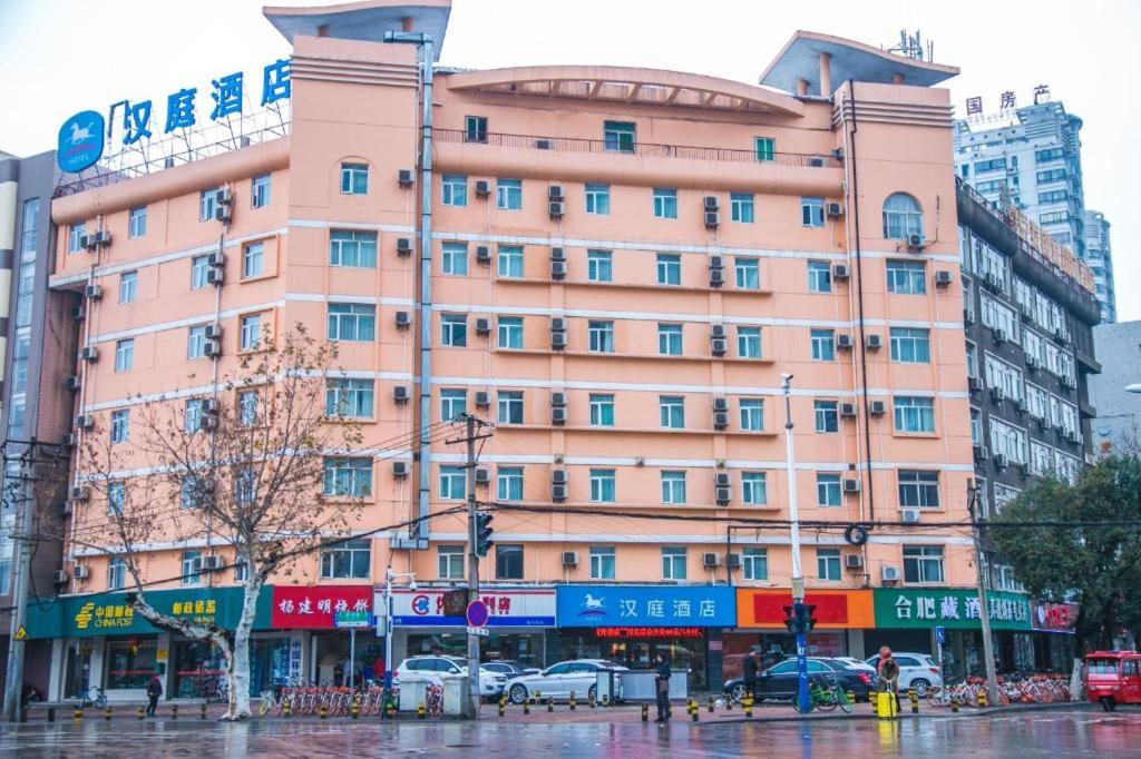 un edificio rosa en una calle de la ciudad bajo la lluvia en Hanting Hotel Hefei Dadongmen Metro Station en Hefei