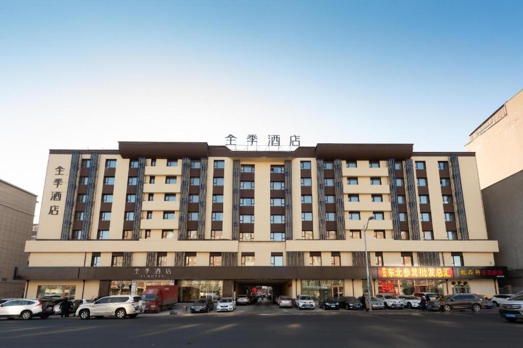 un grande edificio con auto parcheggiate in un parcheggio di Ji Hotel Chuangchun Railway Station a Changchun