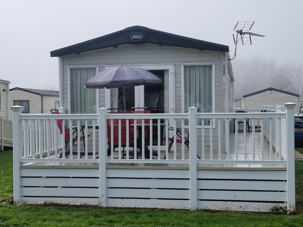 a house with a porch with chairs and an umbrella at Sunnyside lodge in Cirencester