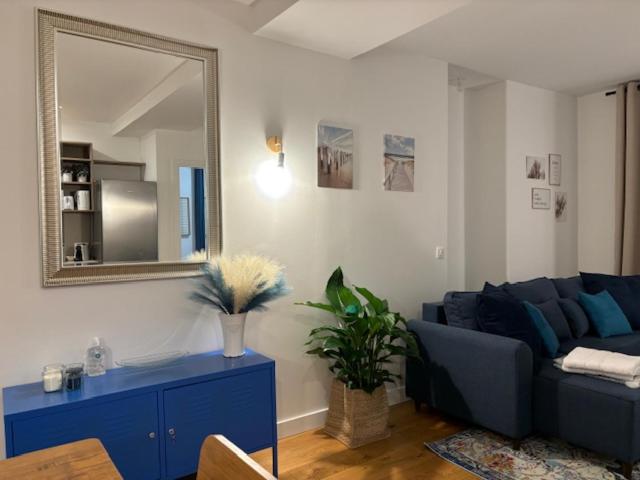 a living room with a blue couch and a mirror at Relax 1 bedroom apartment - EG01 in Enghien-les-Bains