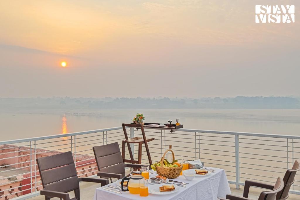 uma mesa numa varanda com vista para a água em StayVista at The Ganga House - Holy River Varanasi em Varanasi