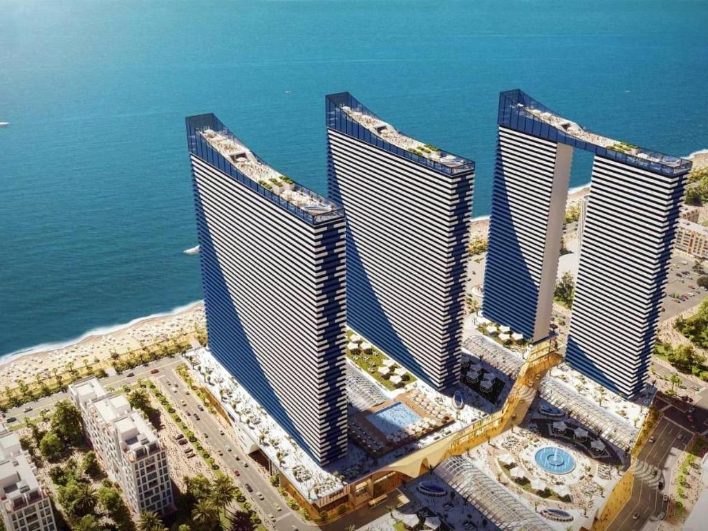 an aerial view of four tall buildings next to the ocean at ORBI CITY - The Shining Apartments in Batumi