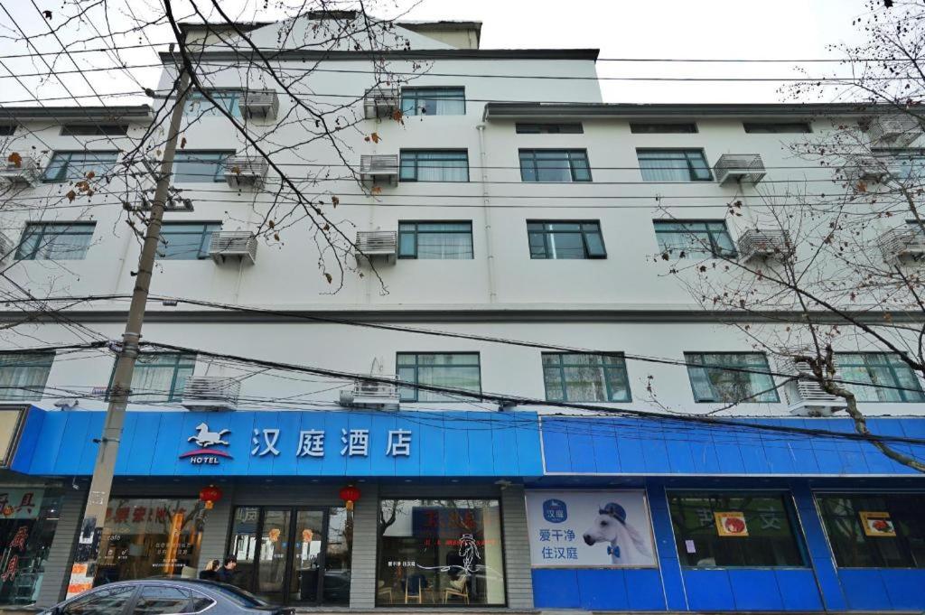 ein großes weißes Gebäude mit einem Schild davor in der Unterkunft Hanting Hotel Suzhou Guanqian Street in Suzhou