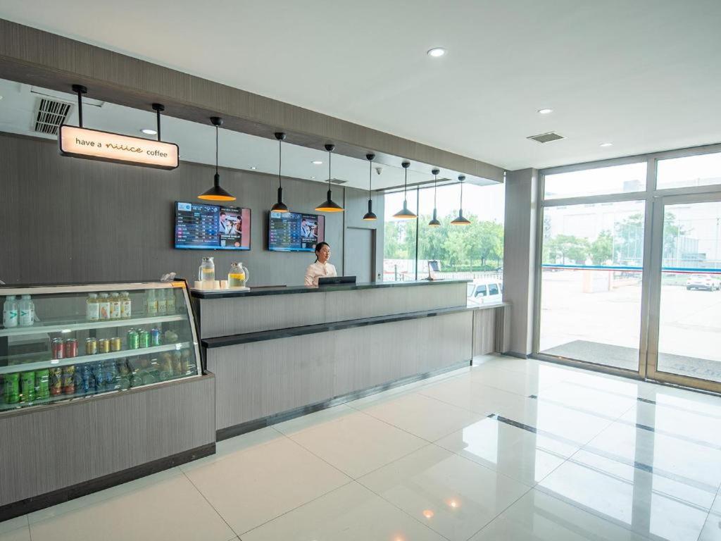 a woman standing at a counter in a restaurant at Hanting Hotel Jiaozhou Jiaodong International Airport in Madian