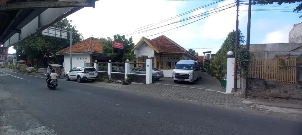 a person riding a motorcycle down a street with cars at Hotel Purnama 5 in Ngaglik