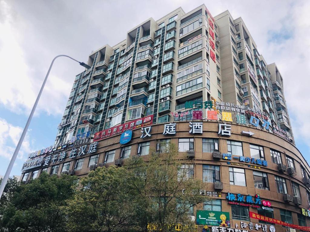 a tall building with colorful signs on it at Hanting Hotel Wenzhou Leqing Liushi Town in Hengdaiqiao